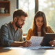 Jeune couple à la cuisine consulte documents et tablette